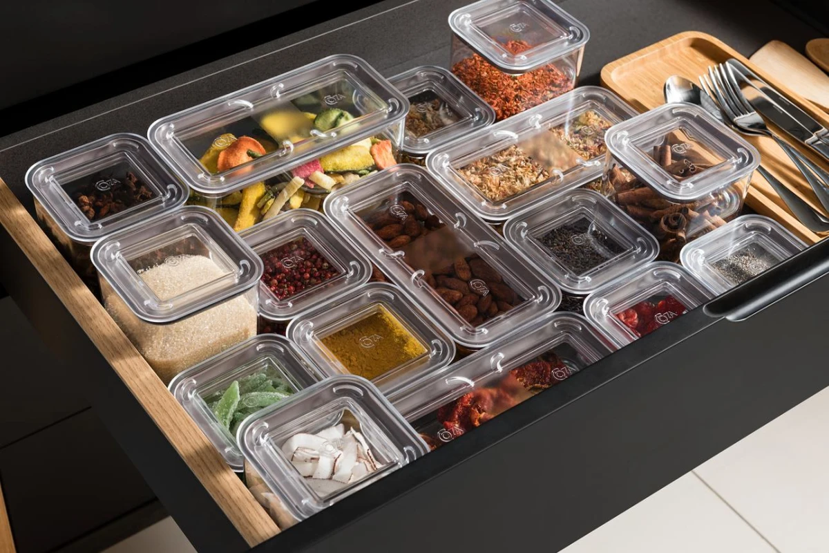 Clear storage containers organizing food and utensils in a kitchen drawer
