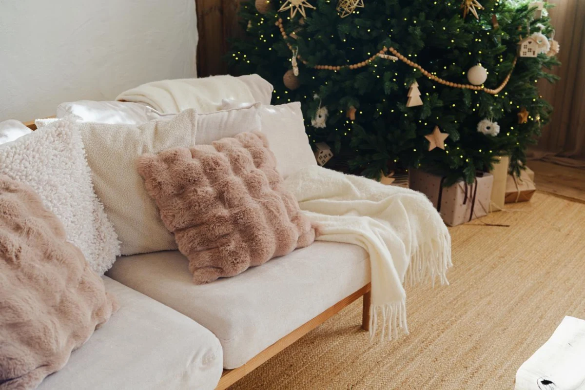 Sofa with soft throws and decorative pillows beside a Christmas tree